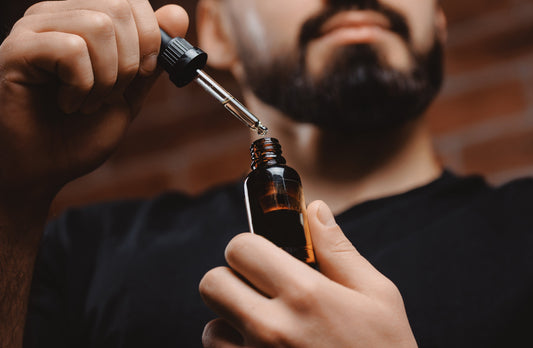 Bearded man holding a bottle of beard oil